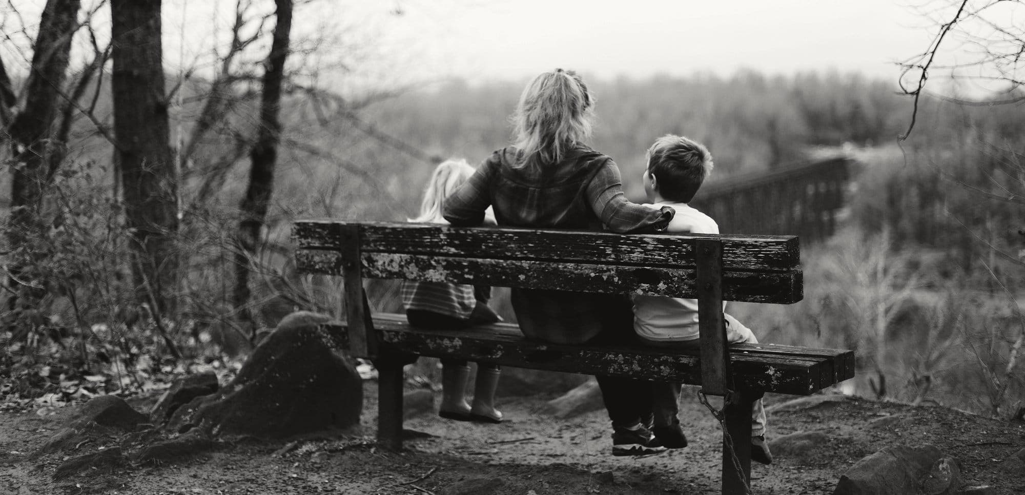 A family of three on a bench, looking out over the hills together